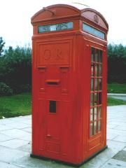Red telephone box with post box in one side.