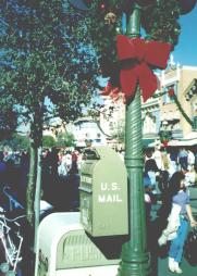 Green U.S. MAIL box attached to a lamp post.